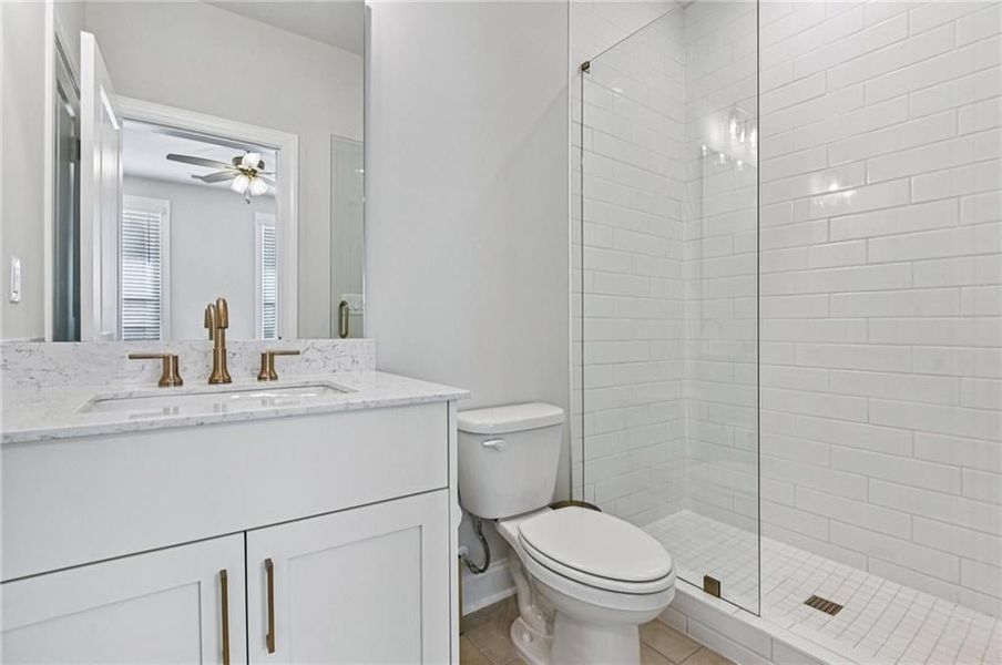 Full bath featuring vanity, a stall shower, light tile patterned floors, and a ceiling fan