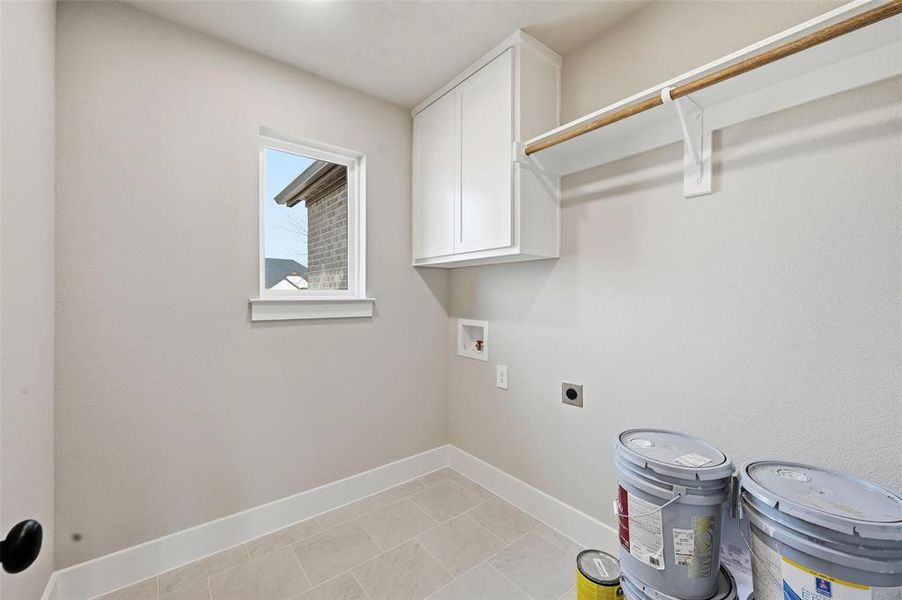Laundry area featuring electric dryer hookup, washer hookup, cabinet space, and light tile patterned floors