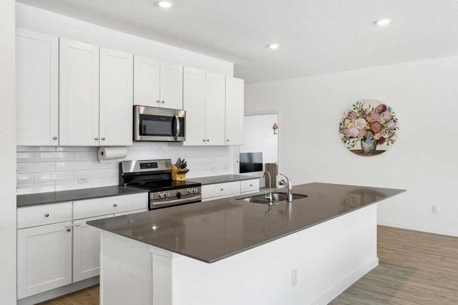 A well-lit kitchen with sleek countertops and ample cabinetry provides an inviting culinary space.