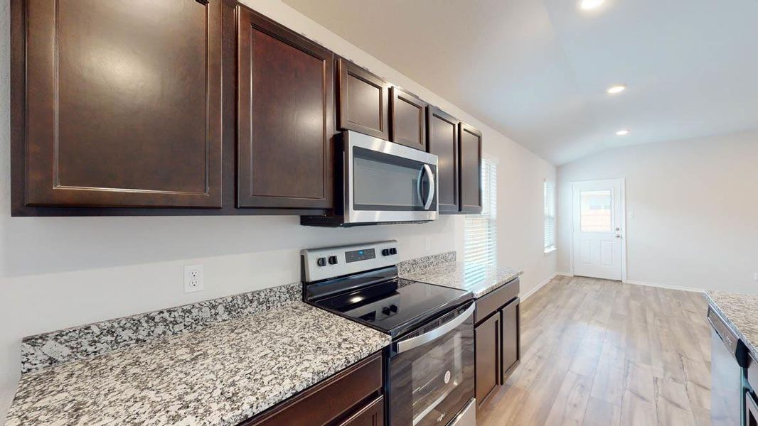 Kitchen featuring dark wood cabinetry, granite-style countertops, stainless steel electric range, and a built-in microwave