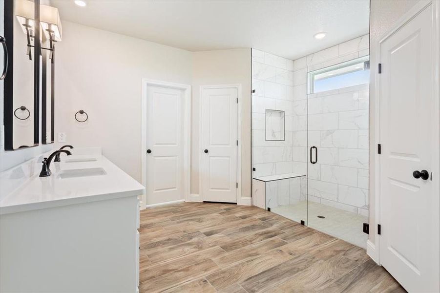 Bathroom with a sink, recessed lighting, double vanity, wood finished floors, and a stall shower