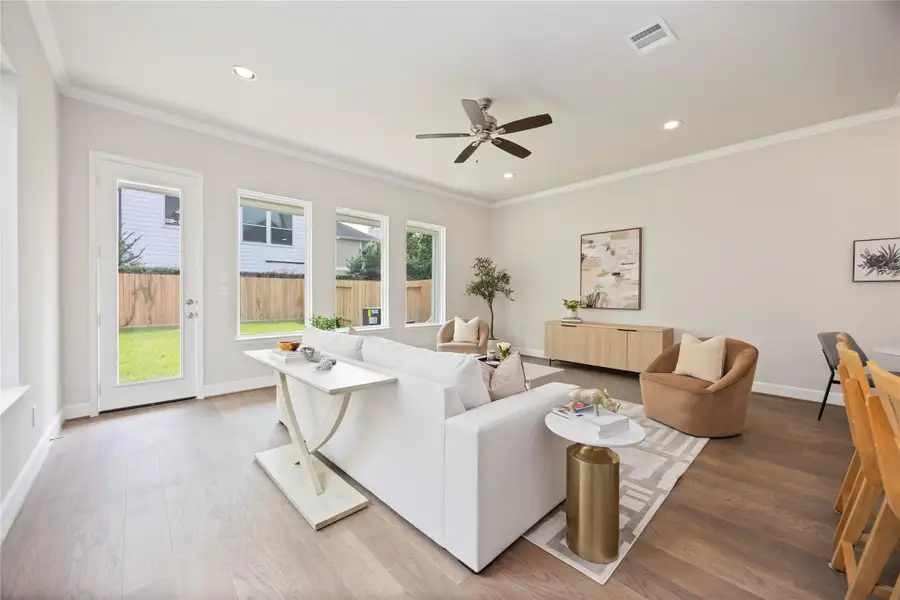 A wall of windows bathes the living room in natural light, offering serene views of the tranquil backyard.