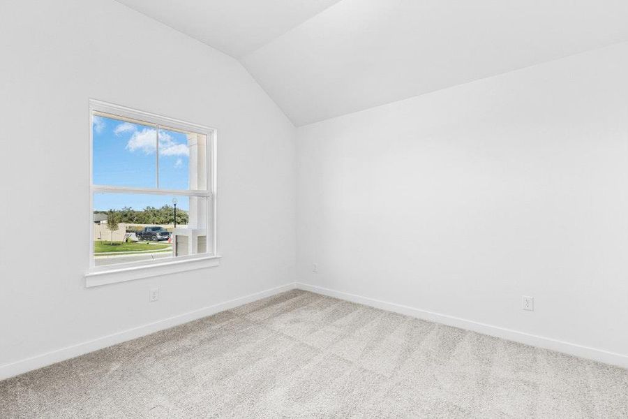 Carpeted empty room featuring lofted ceiling and baseboards