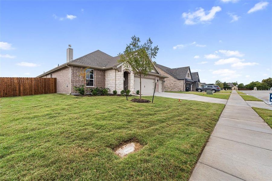 French country inspired facade featuring a chimney, brick siding, concrete driveway, a garage, and roof with shingles French country inspired facade featuring a chimney, brick siding, concrete driveway, a garage, and roof with shingles