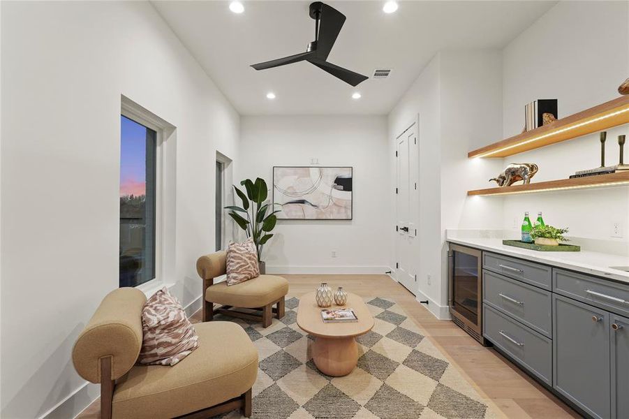 Sitting room featuring light wood-style floors, beverage cooler, recessed lighting, a bar, and a ceiling fan