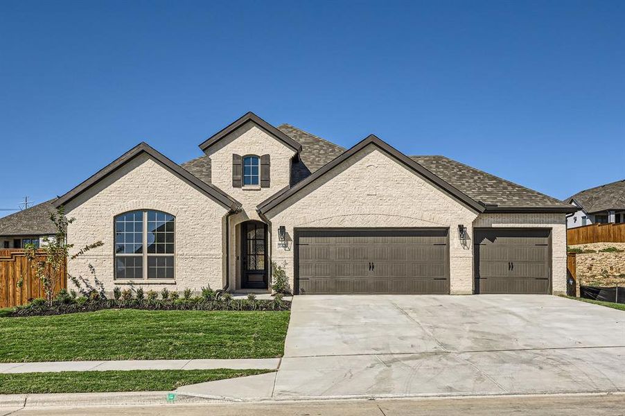 French country inspired facade with a front yard and a garage