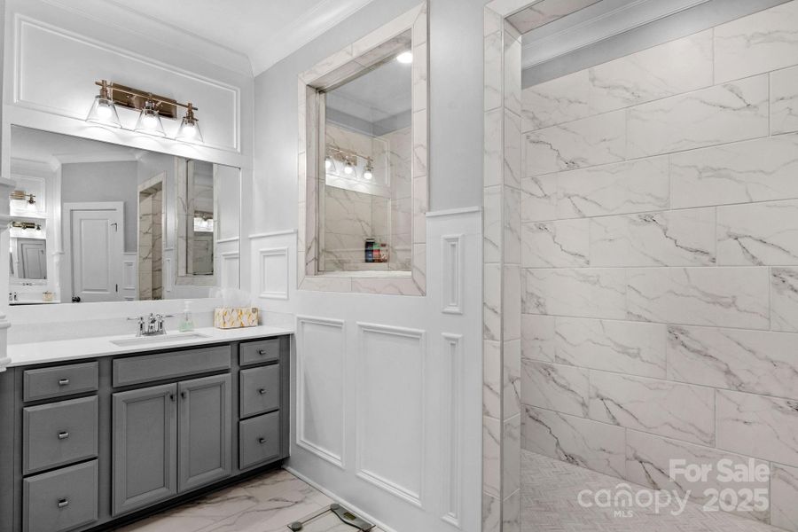 Primary bath with dual vanities and curbless walk-in shower.