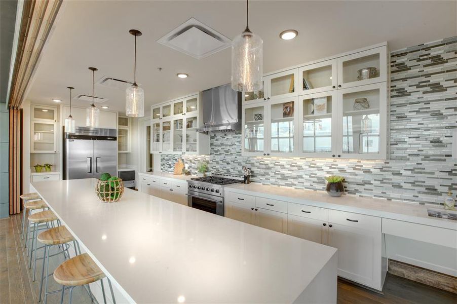 Kitchen featuring range hood, a center island, white cabinets, high quality appliances, and decorative backsplash