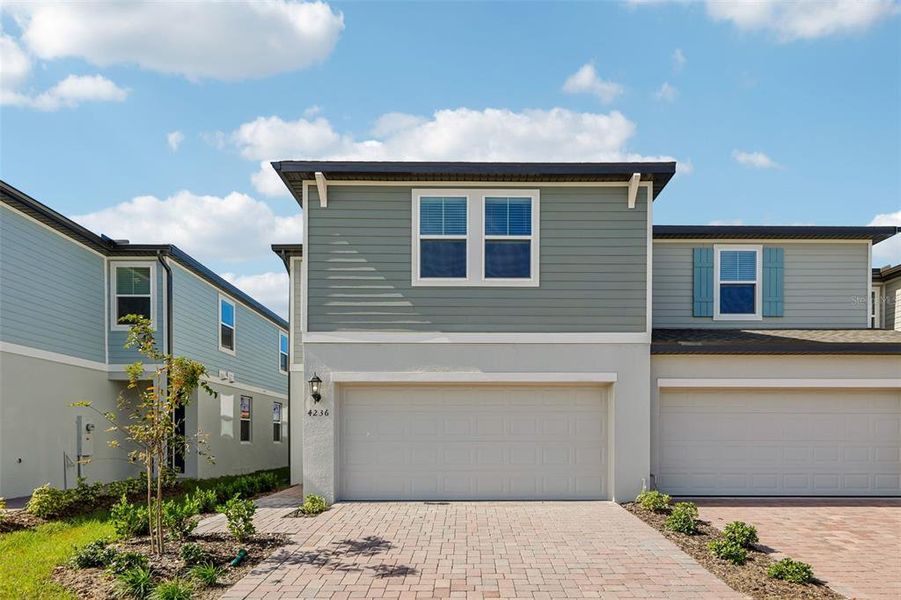 Front exterior of a new home in The Meadow at Crossprairie Townes, St. Cloud, FL, highlighting curb appeal (Image 1). Front exterior of a new home in The Meadow at Crossprairie Townes, St. Cloud, FL, highlighting curb appeal (Image 1).