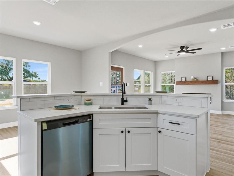 Kitchen with white cabinets, a center island with sink, light wood-style flooring, dishwasher, and ceiling fan Kitchen with white cabinets, a center island with sink, light wood-style flooring, dishwasher, and ceiling fan