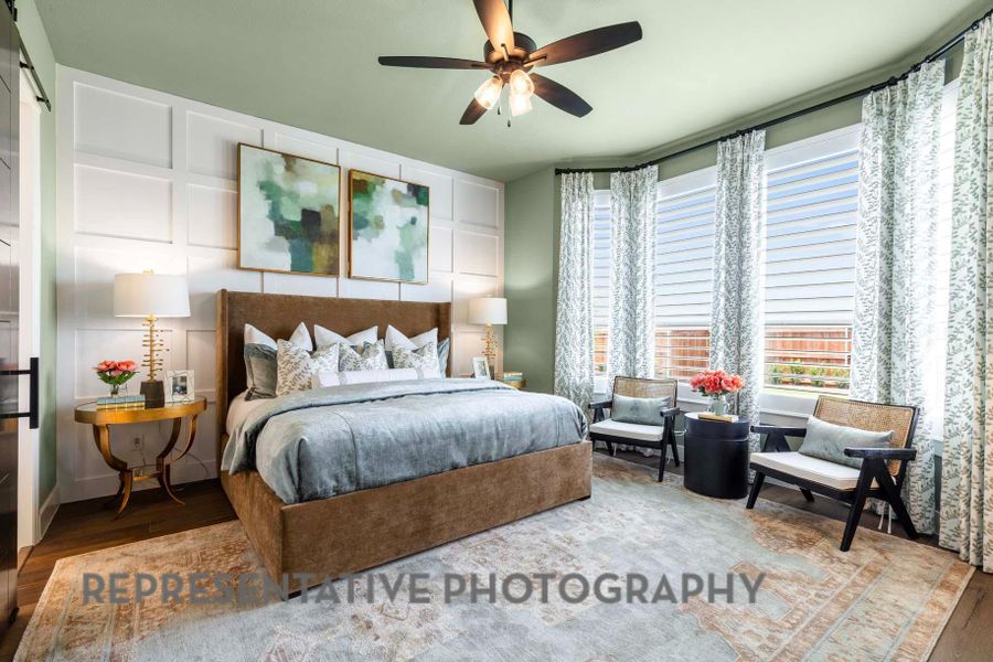 Bedroom featuring wood finished floors, a decorative wall, and a ceiling fan Bedroom featuring wood finished floors, a decorative wall, and a ceiling fan