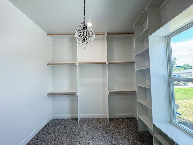 Walk in closet featuring a chandelier and carpet Walk in closet featuring a chandelier and carpet