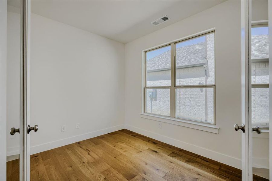 Room featuring wood-finish flooring, a large multi-pane window, white walls, and white trim