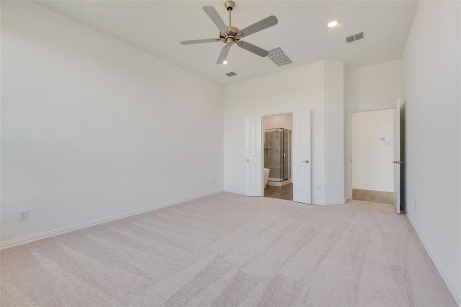 Unfurnished bedroom featuring ceiling fan, light colored carpet, and ensuite bathroom