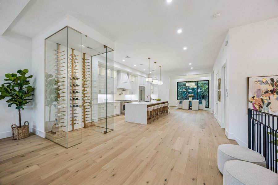 A Floor-to-Ceiling Glass Enclosed Wine Room serves as a Striking Architectural Focal Point between the Living Room and Kitchen. A Floor-to-Ceiling Glass Enclosed Wine Room serves as a Striking Architectural Focal Point between the Living Room and Kitchen.