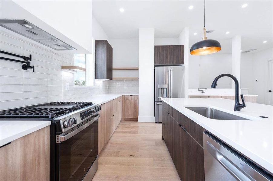 Experience culinary convenience with a sleek pot filler, stylish floating shelves, a high-end Moen disposal system, and a space-saving in-cabinet microwave — all set in a modern, streamlined kitchen.