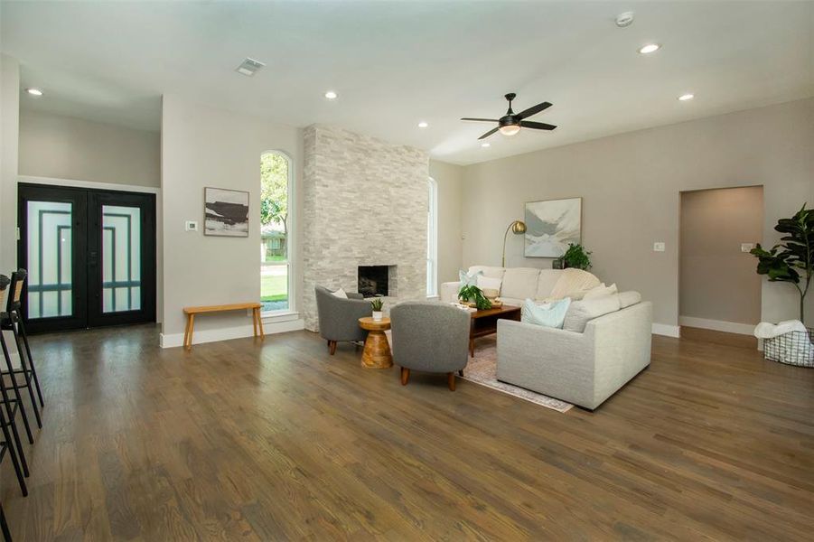 Living room with ceiling fan, dark hardwood / wood-style floors, and a fireplace