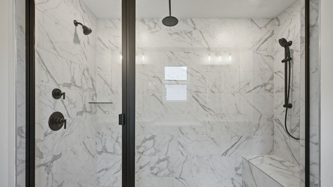 Full tiled shower with glass door and multiple showerheads and bench seat Full tiled shower with glass door and multiple showerheads and bench seat