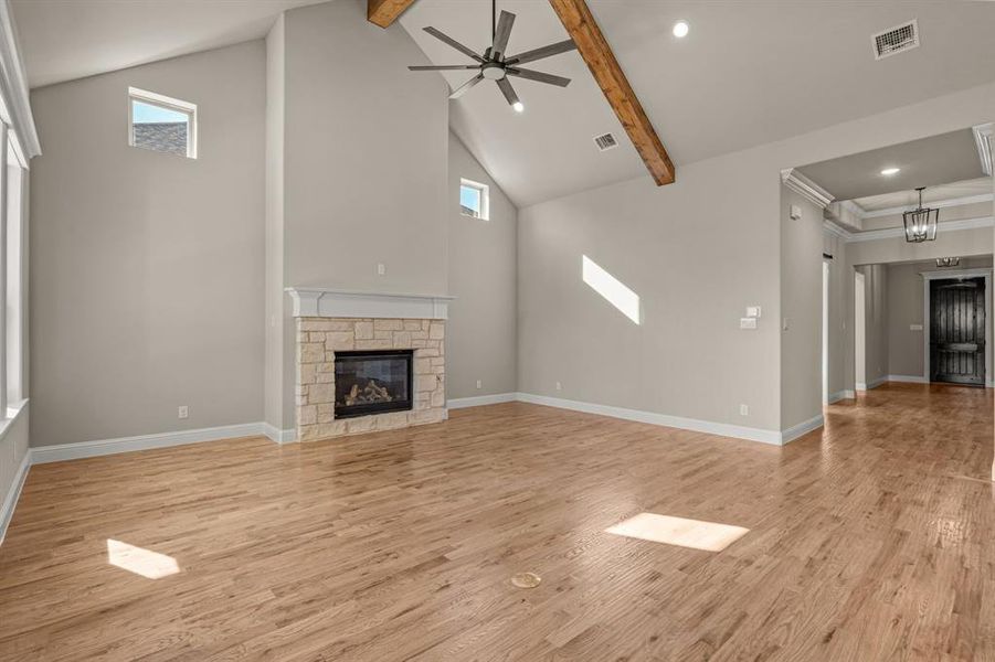 Unfurnished living room with high vaulted ceiling, light wood-type flooring, beamed ceiling, ceiling fan, and a fireplace