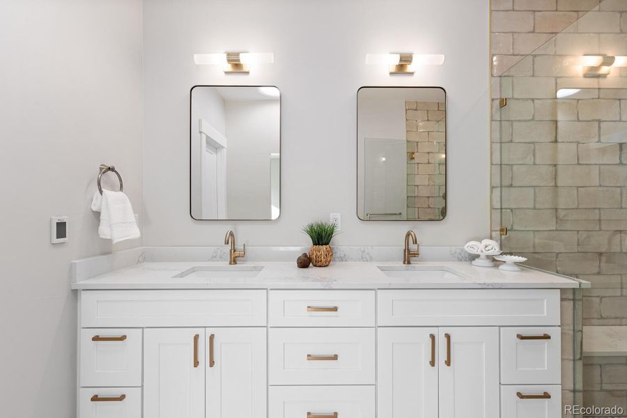 Primary bathroom with double vanities, customtile, glass enclosure, and tubular skylight Primary bathroom with double vanities, customtile, glass enclosure, and tubular skylight