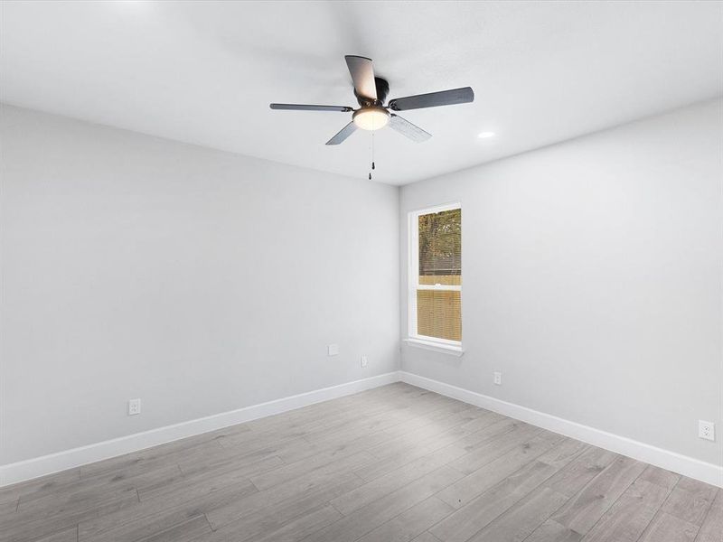 Empty room featuring light wood finished floors, ceiling fan, and recessed lighting
