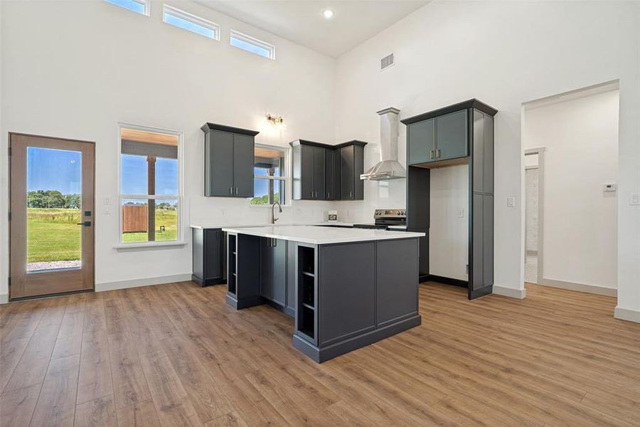 Spacious kitchen featuring an island with built-in shelving, dark cabinetry, and white countertops