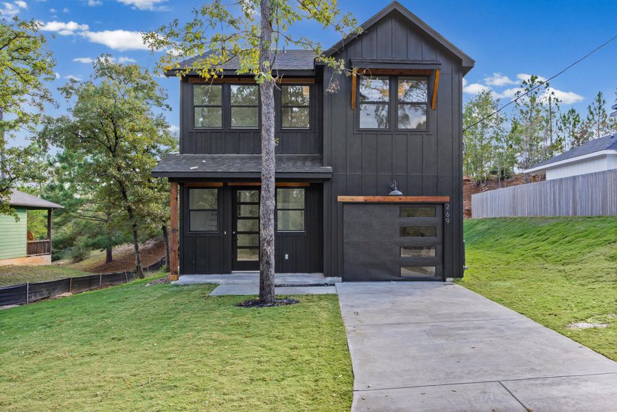 View of front of property featuring board and batten siding, driveway, and an attached garage