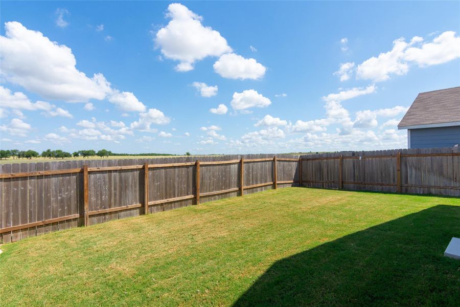 Expansive rear lawn featuring a full privacy fence