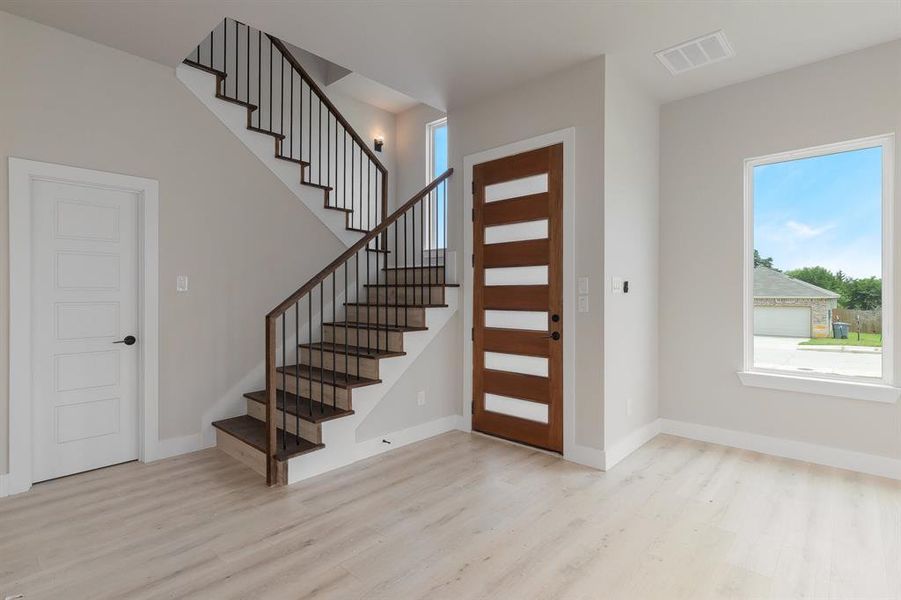 Foyer entrance with wood finished floors, stairs, and baseboards