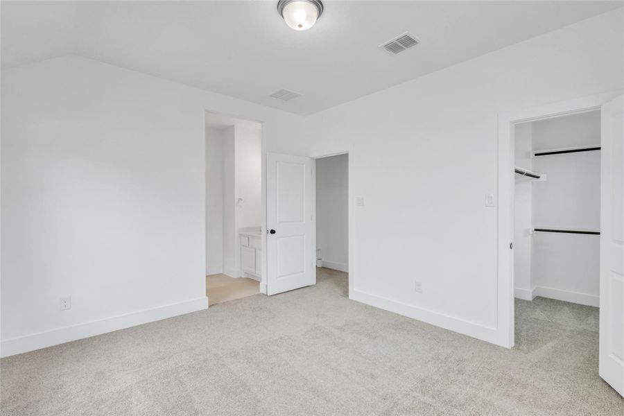 A spacious, naturally illuminated room featuring plush carpeting and crisp white walls.