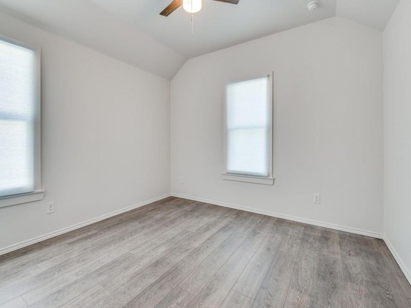 Empty room with ceiling fan, vaulted ceiling, hardwood / wood-style floors, and a healthy amount of sunlight