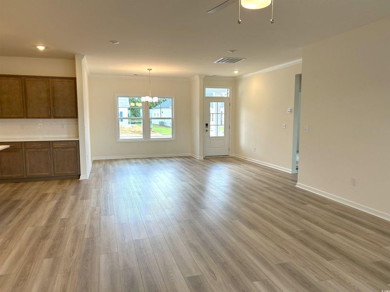 Unfurnished living room with crown molding, light wood-style floors, ceiling fan, and a chandelier