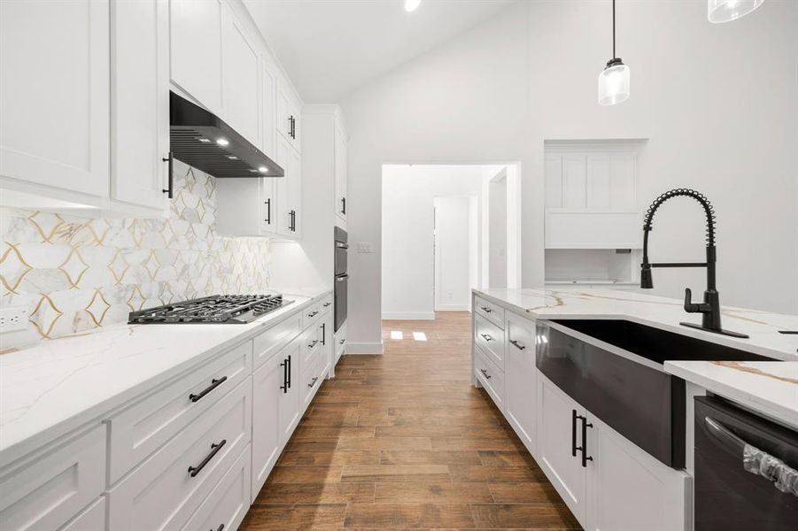 Bright kitchen featuring white shaker cabinetry, quartz countertops, a gas range, a black farmhouse sink, and wood-finish flooring Bright kitchen featuring white shaker cabinetry, quartz countertops, a gas range, a black farmhouse sink, and wood-finish flooring