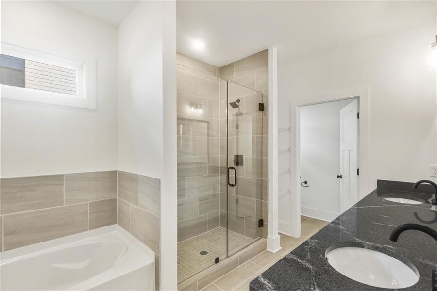 A glass-enclosed shower, built-in tub, and double