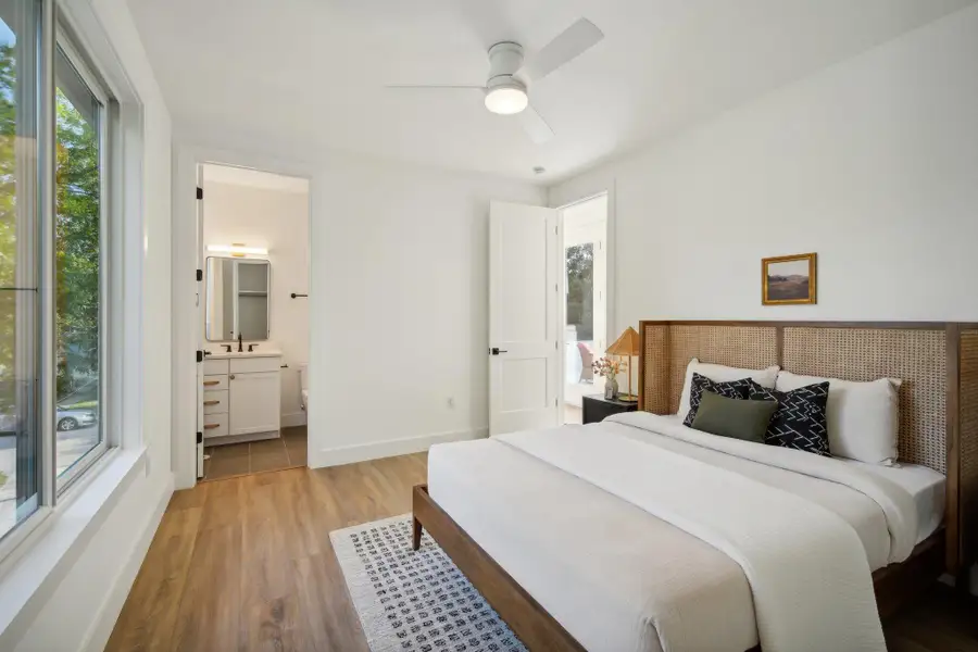 Bedroom with wood finished floors, a ceiling fan, and ensuite bath