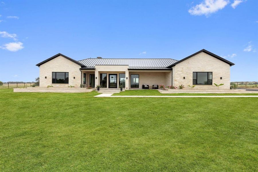 Back of house with stone siding, a standing seam
roof, a metal roof, and covered porch Back of house with stone siding, a standing seam
roof, a metal roof, and covered porch