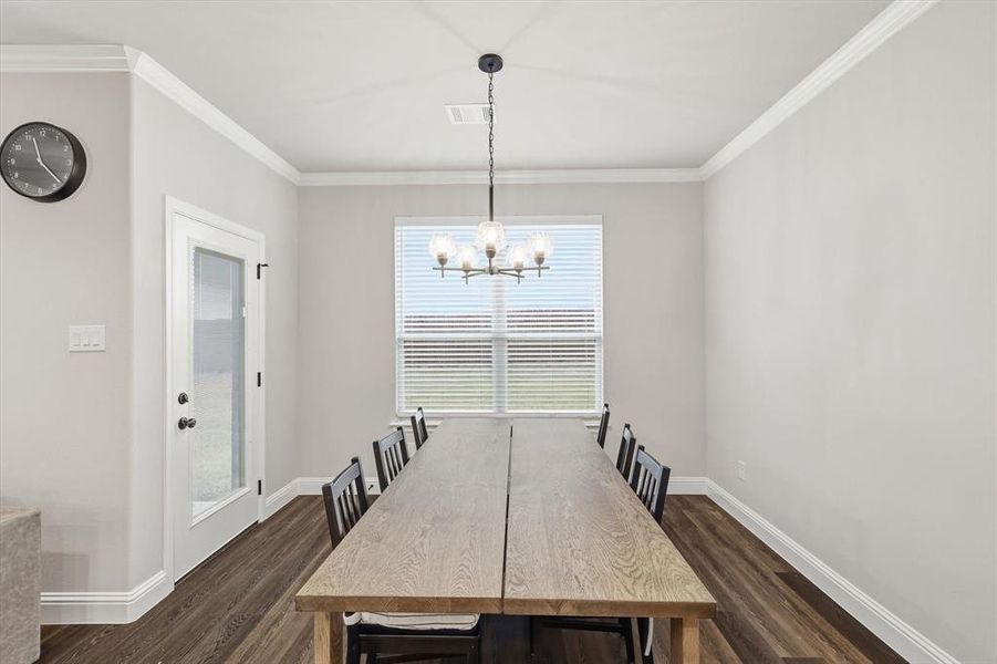 Unfurnished dining area featuring ornamental molding, dark wood-style floors, and a chandelier