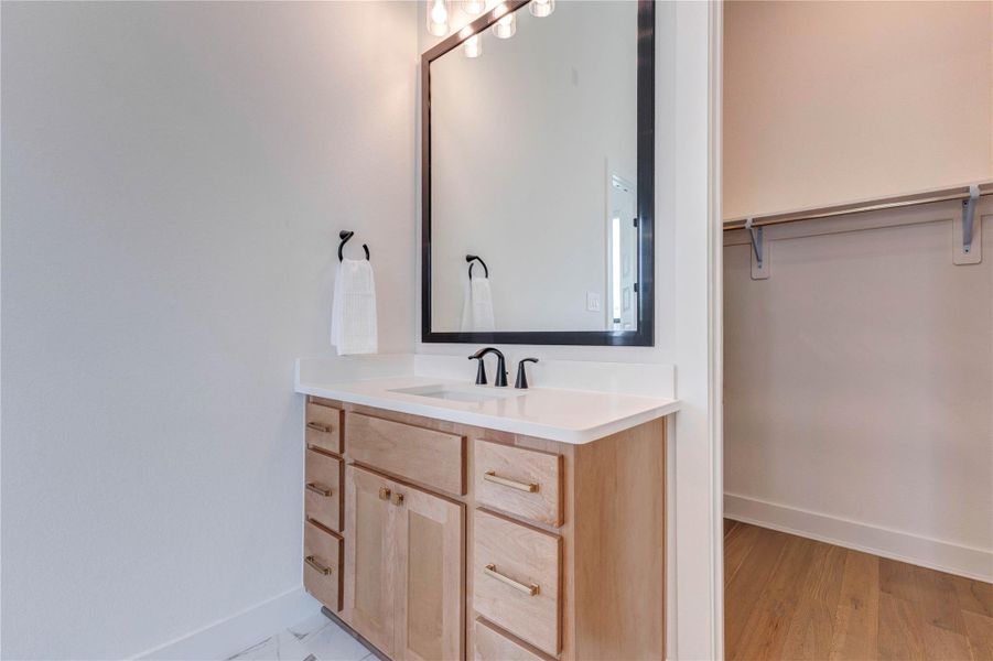 This bathroom features a modern vanity with a sleek black faucet, a large mirror, and ample storage. The light wood cabinetry and white countertop create a bright and clean look. This bathroom features a modern vanity with a sleek black faucet, a large mirror, and ample storage. The light wood cabinetry and white countertop create a bright and clean look.