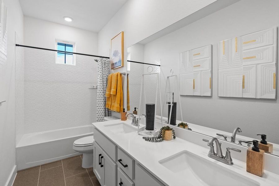 Full bath with double vanity, shower / bath combo with shower curtain, and dark tile patterned floors