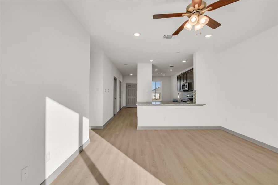 Unfurnished living room featuring light wood-type flooring, a ceiling fan, and recessed lighting