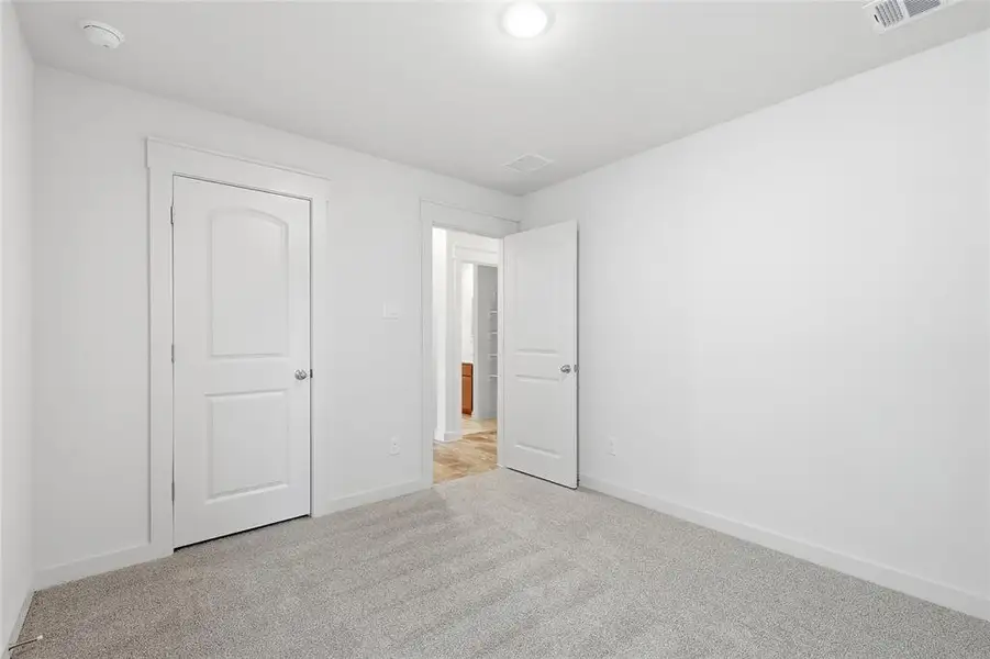 Unfurnished bedroom with light colored carpet and baseboards Unfurnished bedroom with light colored carpet and baseboards