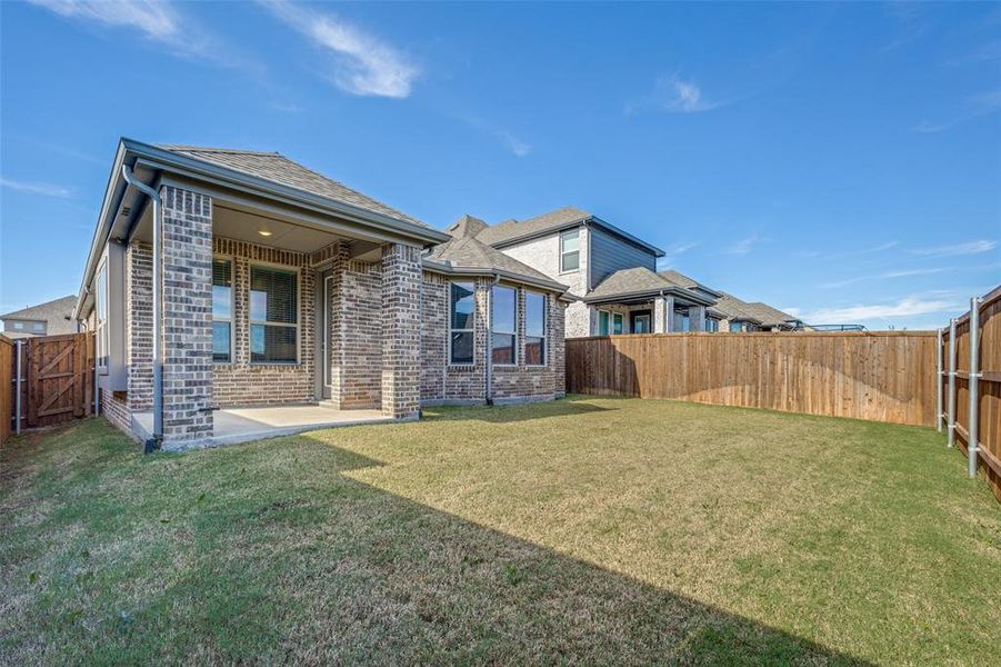 Rear view of property with a fenced backyard, a patio area, a gate, brick siding, and a shingled roof