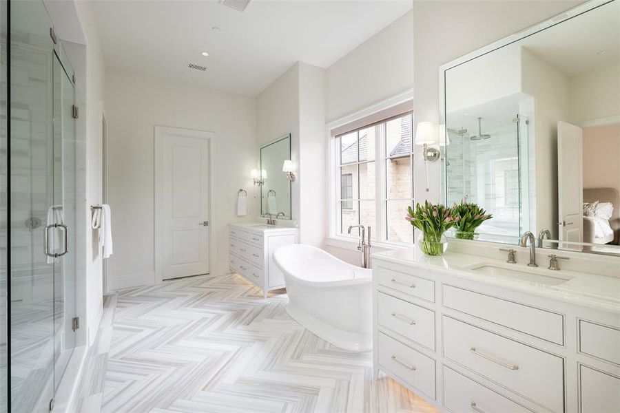Primary bathroom with dual vanities, stand alone tub, and separate shower