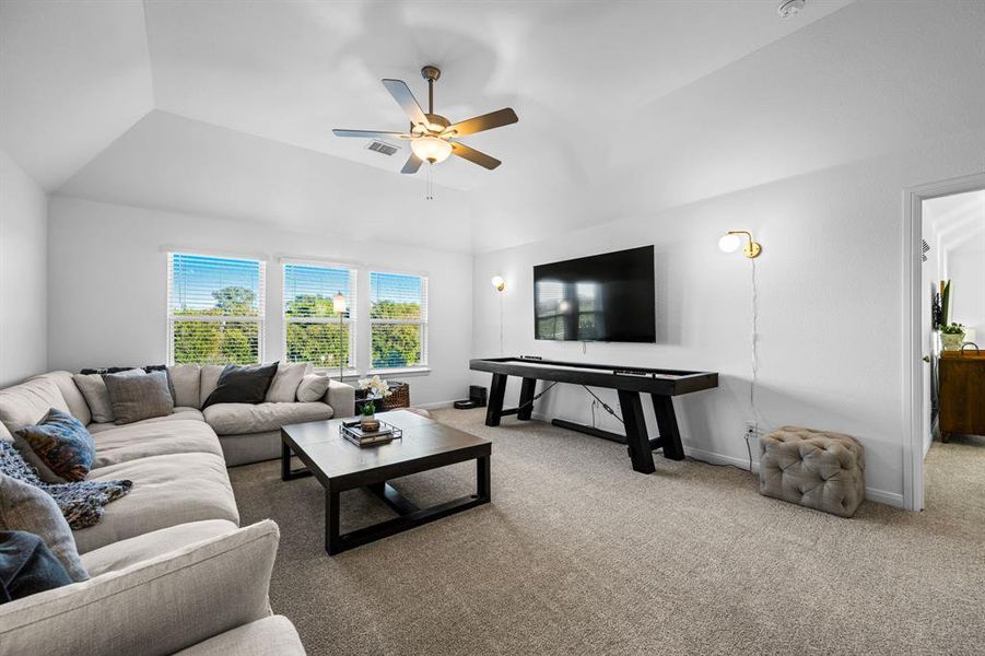 Upstairs living room with a vaulted ceiling and a ceiling fan Upstairs living room with a vaulted ceiling and a ceiling fan