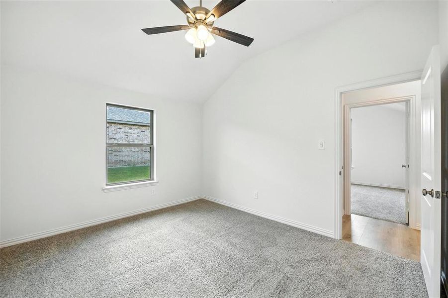 Spare room featuring light carpet, a ceiling fan, and vaulted ceiling