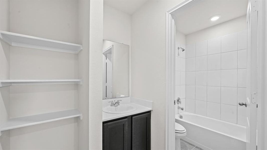Bathroom featuring a dark vanity with a white countertop, an integrated sink, and a framed mirror