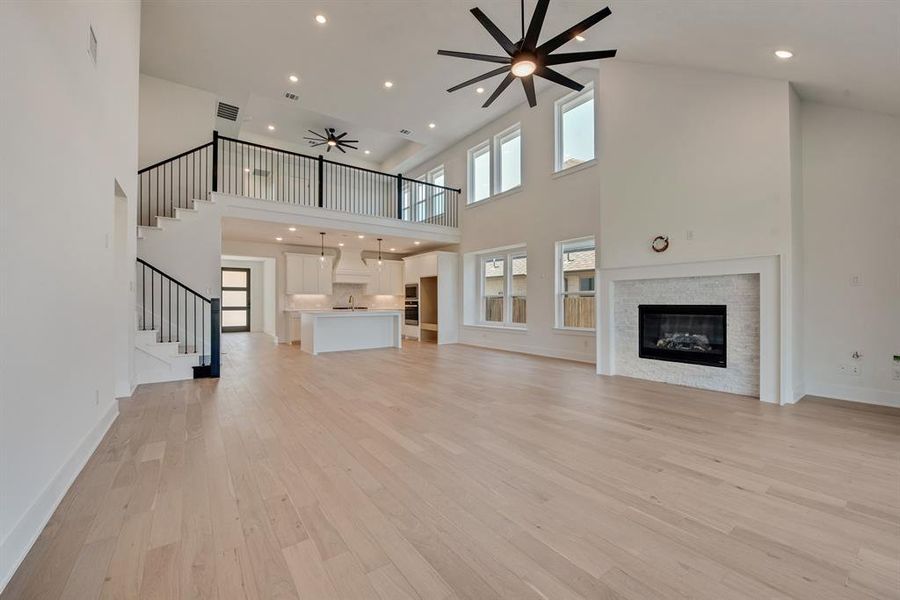 Unfurnished living room featuring stairs, light wood finished floors, recessed lighting, a glass covered fireplace, and ceiling fan Unfurnished living room featuring stairs, light wood finished floors, recessed lighting, a glass covered fireplace, and ceiling fan