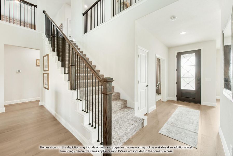 Bright two-story foyer with carpeted staircase, iron balusters, wood floors, and glass-panel front door Bright two-story foyer with carpeted staircase, iron balusters, wood floors, and glass-panel front door