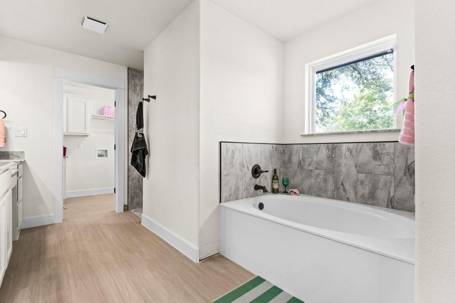 Bathroom with vanity, light wood-style flooring, a bath, and a walk in closet