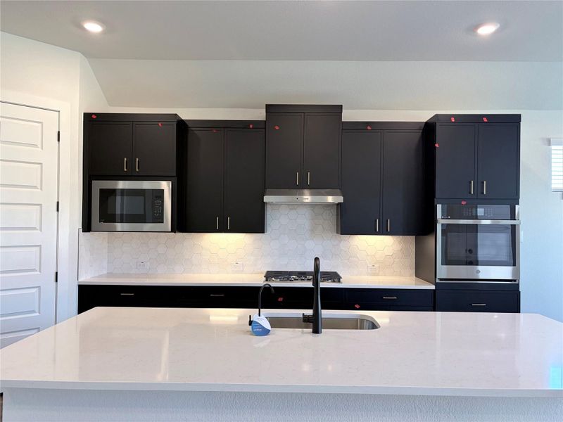 Dark cabinetry beautifully contrasts with light stone countertops in this modern culinary space. Dark cabinetry beautifully contrasts with light stone countertops in this modern culinary space.